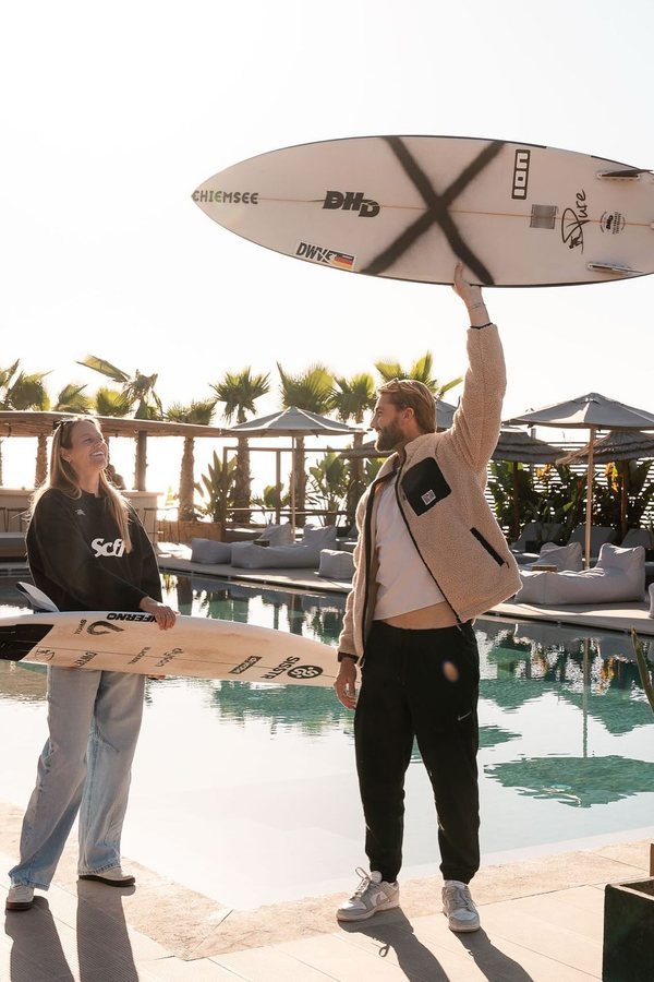 Guests with surfboards beside the pool