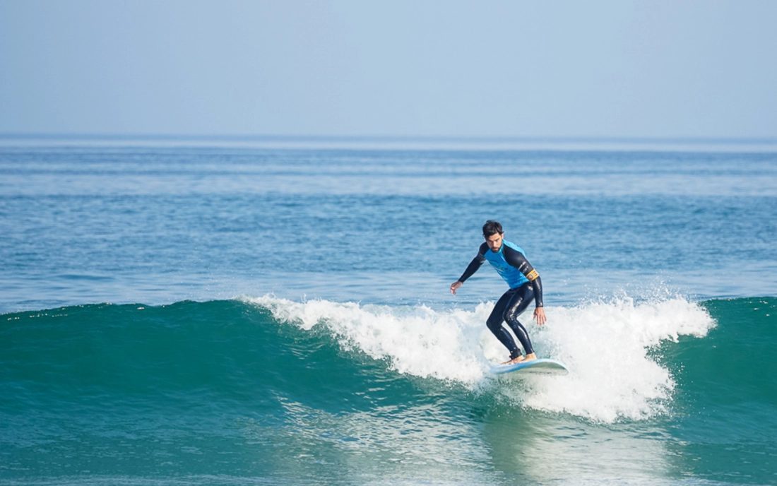 An intermediate surfer riding a green wave