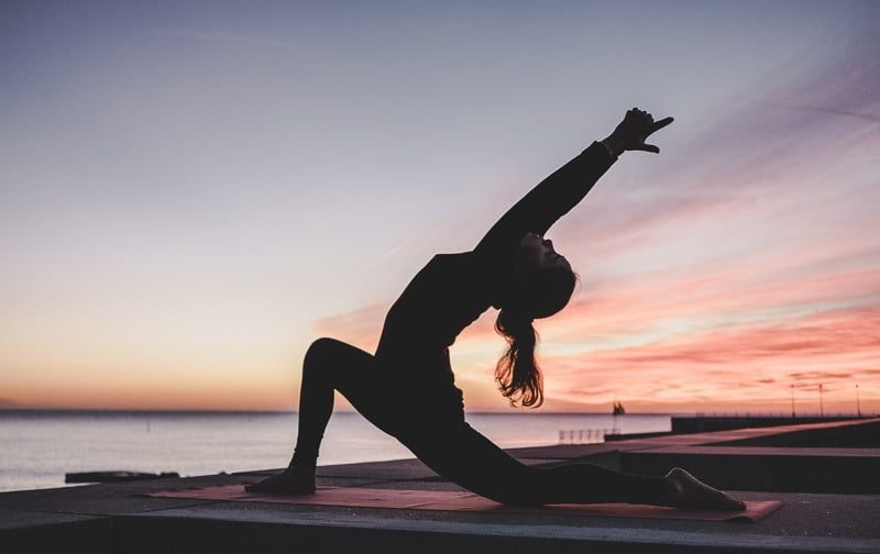 A yoga pose on a mat above the sea at sunset